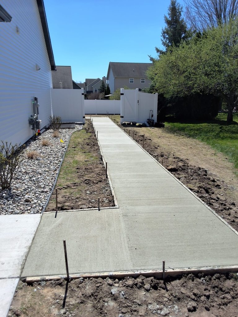 New concrete sidewalk along side of house leading to backyard.